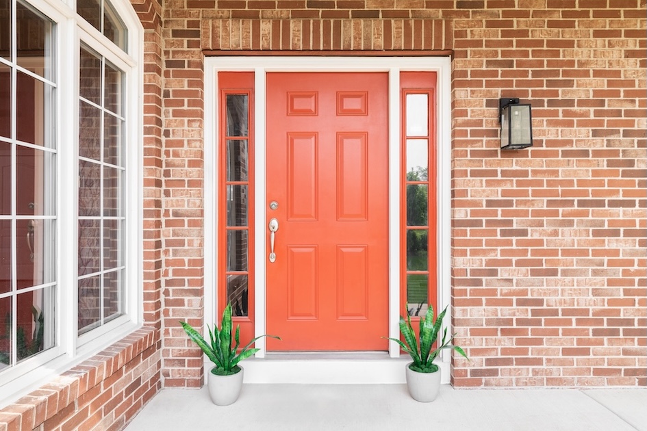 red front door with two small potted plants